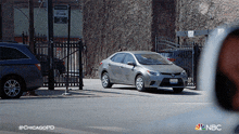 a gray car is parked on the side of the road in front of a fence with a sign that says no parking