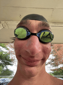 a young man wearing swimming goggles and a swim cap makes a funny face