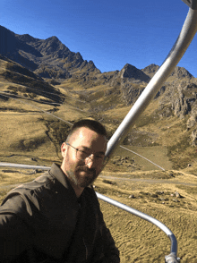 a man wearing glasses is riding a ski lift