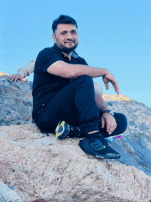 a man sits on a rock wearing a pair of black adidas shoes