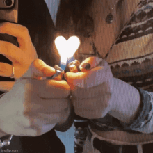 a person is lighting a heart shaped lighter with a heart shaped flame .