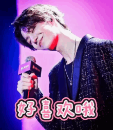 a man is singing into a microphone with chinese writing behind him