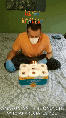 a man wearing a mask and gloves is sitting in front of a birthday cake made out of toilet paper rolls