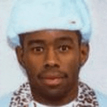 a close up of a man wearing a blue hat and a leopard print scarf .