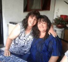 two women posing for a photo with one wearing a blue shirt