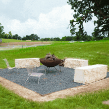 a fire pit sits in the middle of a grassy area