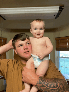 a man holds a baby in a diaper on his shoulder