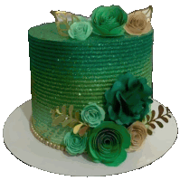 a green cake decorated with green flowers and gold leaves