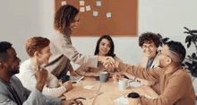 a group of people are shaking hands at a table .