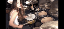 a woman playing a drum set with a picture of a drummer on the screen