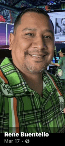 a man in a green plaid shirt is smiling for the camera