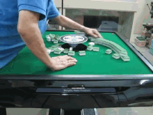 a man in a blue shirt is playing a game of mahjong on a table made by tungbo new products