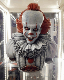 a bust of pennywise the clown from it sits in a glass case