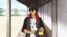 a man in a black and red jacket is holding a cat and a yellow bag