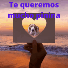 a person is holding a card with a picture of a dog and the words te queremos mucho pinina above it