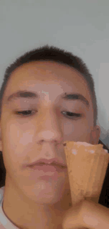 a young man is eating an ice cream cone and making a funny face