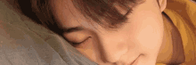 a close up of a young man sleeping on a pillow with his eyes closed .