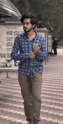 a man in a blue plaid shirt stands in front of a sign that says ' russian karate '