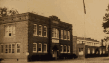 a black and white photo of a brick building with a sign on the front that says ' smith 's memorial school '