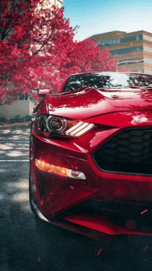 a red car is parked in front of a building and trees