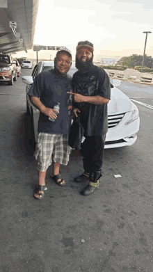 two men standing in front of a white car with one wearing a shirt that says jack daniels