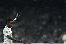 a soccer player in a fly emirates shirt holds up his index finger