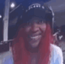 a woman with red hair and a black hat is smiling .