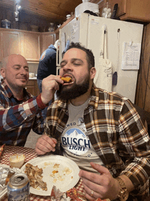 a man wearing a busch light shirt is eating