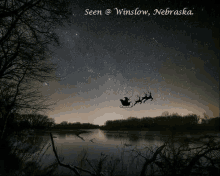 santa claus is flying in a sleigh with reindeer over a lake in nebraska .