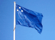 a blue flag with three white stars flying in the wind