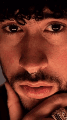 a close up of a man 's face with a beard and a nose ring .