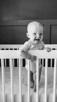 a baby is standing in a crib and making a funny face