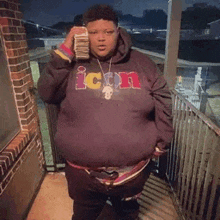 a man in a purple hoodie is holding a bunch of money .