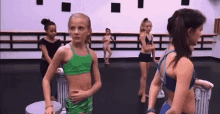 a group of young girls are standing in a dance studio wearing bikinis .