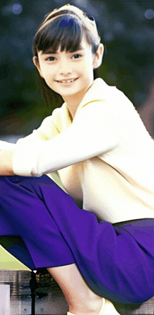 a young girl wearing purple pants and a white shirt