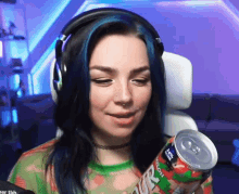 a woman with blue hair is wearing headphones and holding a can of juice