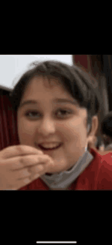 a girl in a red shirt is eating a piece of food and smiling .