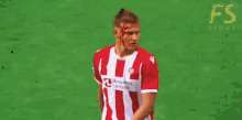 a soccer player in a red and white striped shirt stands next to a referee in a yellow shirt .