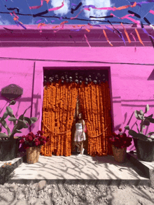 a woman stands in front of a pink building that has a sign that says ' la laguna ' on it