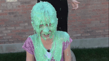 a girl is covered in green slime and has a pink shirt on