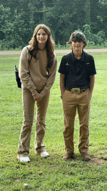 a boy and a girl are posing for a picture in a grassy field