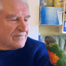 an elderly man holds a colorful parrot on his shoulder with the words hop pillu written on the bottom right