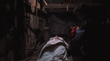 a man is holding a chainsaw in a dark room with a person chained to the floor