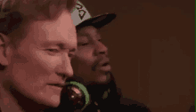 snoop dogg and conan o'brien are sitting next to each other wearing headphones and hats .