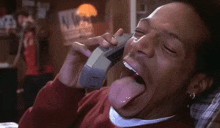 a man sticking his tongue out while talking on a phone