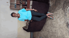 a woman in a blue shirt and black pants laying on a couch