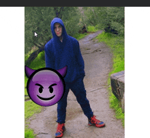 a man in a blue hoodie stands next to a purple devil face