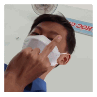 a man wearing a face mask shows the middle finger