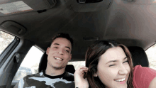 a man and a woman are sitting in a car with a warning label on the roof