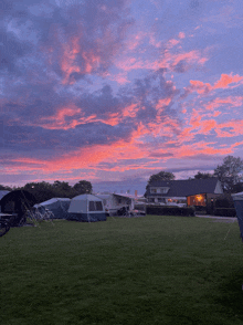 a sunset over a campground with a house in the background